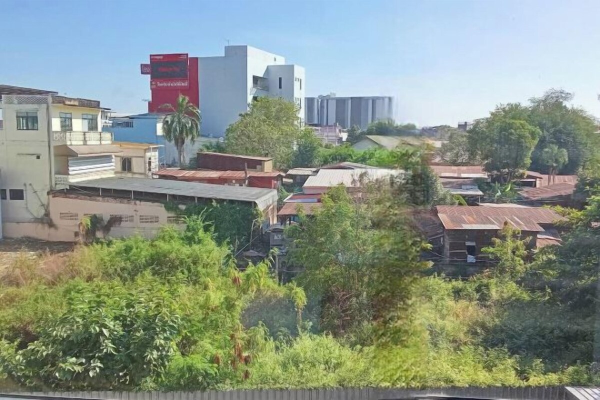 Una zona residencial con diversos edificios, incluyendo una estructura destacada roja y blanca, rodeada de vegetación y árboles.