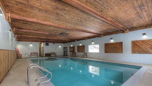 An indoor swimming pool with wooden beams on the ceiling, a metal ladder, and a tiled floor. - Cute condo w/fireplace, private decks & community pool/hot tub/sauna - Cozy Curley Bear Condo (Big Sky)