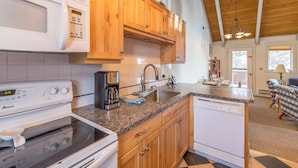 A kitchen with wooden cabinets, a microwave, a stove, a dishwasher, and a coffee maker. - Cute condo w/fireplace, private decks & community pool/hot tub/sauna - Cozy Curley Bear Condo (Big Sky)