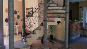 Una scala con ringhiere in metallo decorate, colonne in pietra e una pianta in vaso.