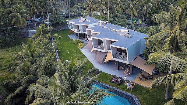 A modern multi-story building with a flat roof, surrounded by lush greenery and palm trees. - Mahi Mahi Dive Resort (Zamboanguita)