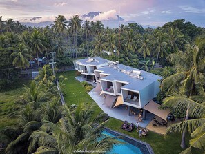 A modern multi-story building with a flat roof, surrounded by lush greenery and palm trees. - Mahi Mahi Dive Resort (Zamboanguita)