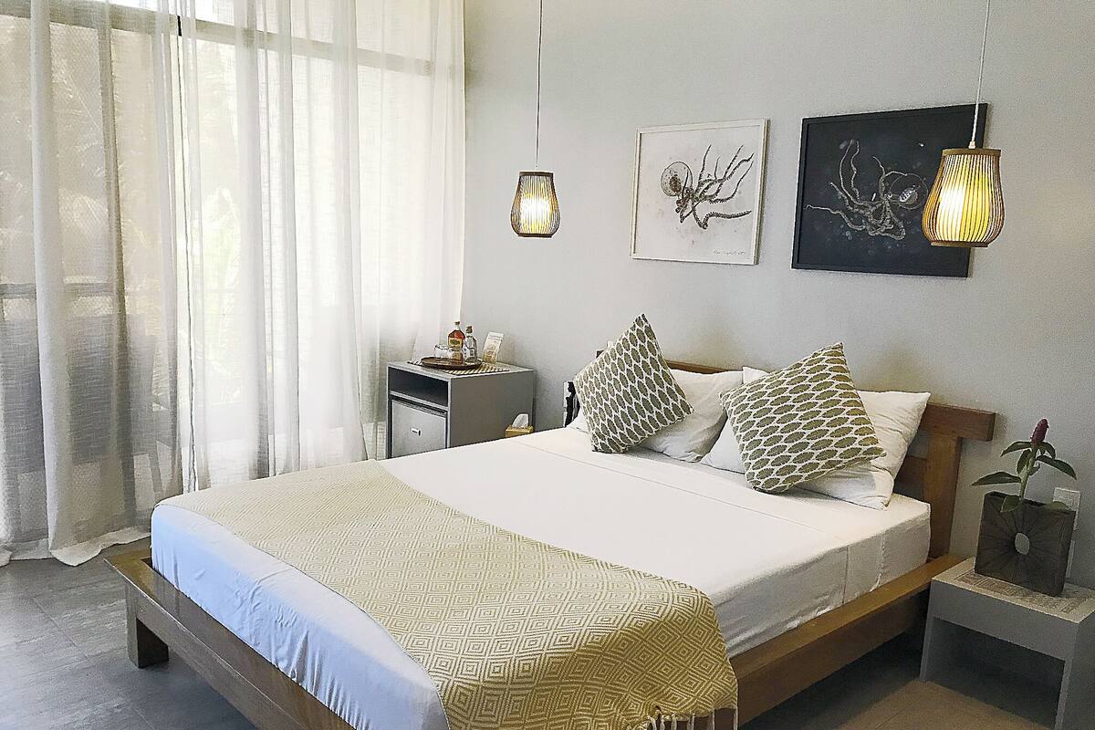 A neatly arranged bedroom with a bed, bedside tables, and artwork on the walls.
