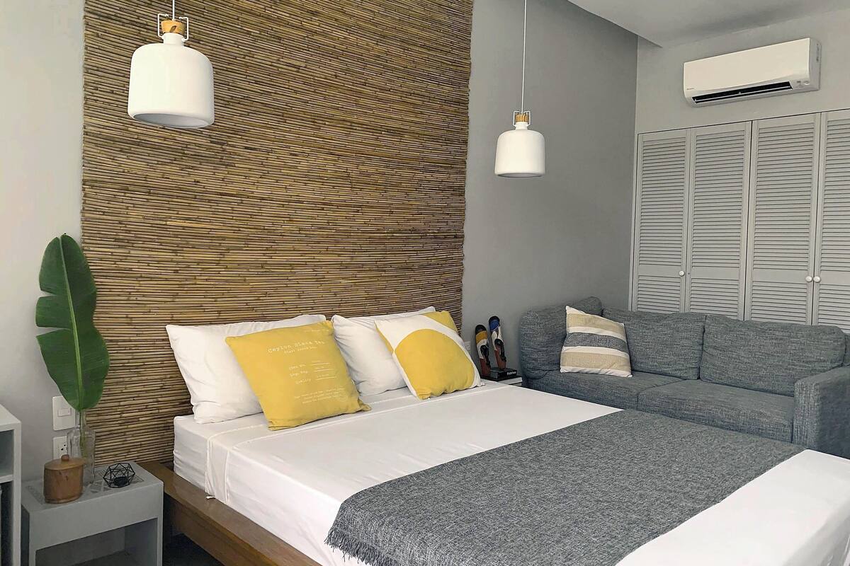 A modern bedroom with a bed, bedside table, and a grey sofa.