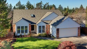 Ein zweigeschossiges Haus mit Garage, überdachter Veranda und gepflegtem Rasen.