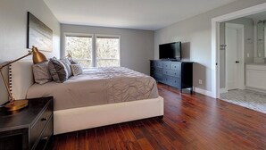 Ein Schlafzimmer mit einem Bett, einem Schminktisch, einem Fernseher und einer Tür zu einem Badezimmer.