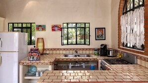 Une cuisine avec un mur recouvert de carreaux, un réfrigérateur, une cuisinière et un évier.