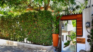 Une villa nommée «Villa Isabella», dotée d’une porte d’entrée en bois, d’un chemin en béton et d’une végétation luxuriante.