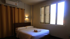 A hotel room with a bed, curtains, an air conditioning unit, and a window with blinds. - Botanic Garden Nan Guest House (Pua)