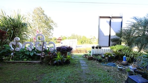 A garden with various plants, a metal sculpture, and a water feature. - Botanic Garden Nan Guest House (Pua)