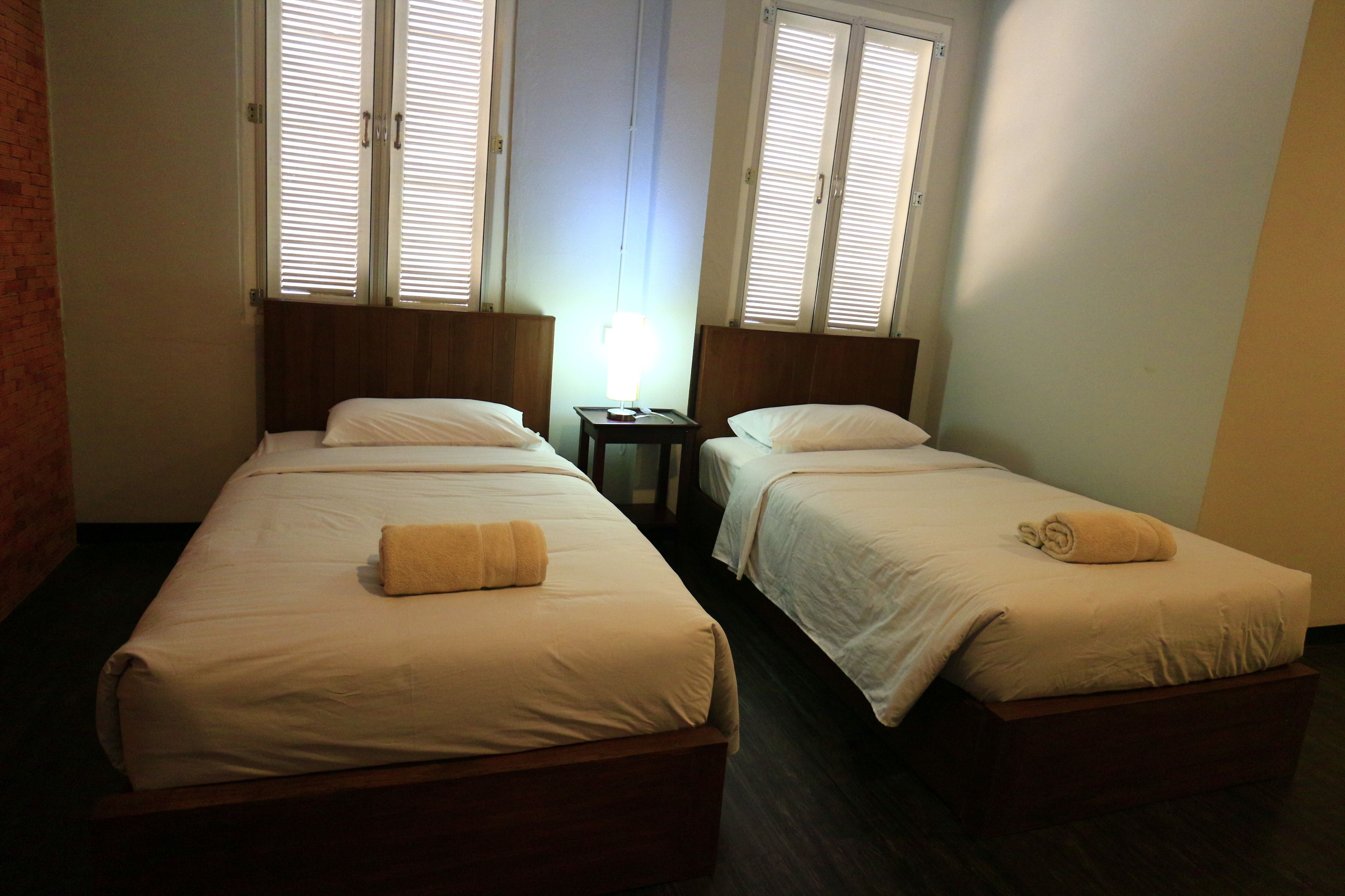 Una habitación de hotel con dos camas individuales, una mesita de noche y una lámpara.