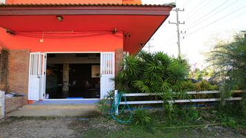 Um edifício com fachada vermelha, porta branca e um pequeno alpendre.