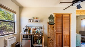 Eine kompakte Küche mit Kühlschrank, Mikrowelle, Kaffeemaschine und einer kleinen Spüle.