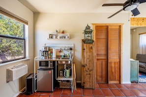 A compact kitchen with a refrigerator, microwave, coffee maker, and a small sink.