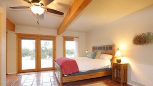 Ein Schlafzimmer mit einem Bett, einem Nachttisch, einer Lampe und einem Deckenventilator.