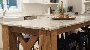 A kitchen with a large island, white cabinets, and pendant lighting. - North Pine Cottage #1 (Brainerd)