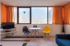A modern living room with a TV, two chairs, a small table, and a sofa. - cube (Osaka)