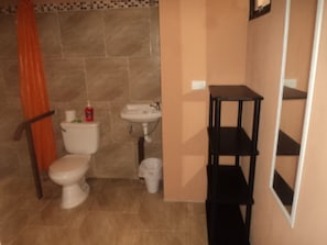 A bathroom with a toilet, sink, and a black shelf unit.