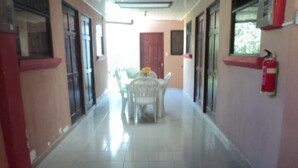 A corridor with a tiled floor, a red carpet, and a table with chairs in the center. - Casa Maya (Monteverde)