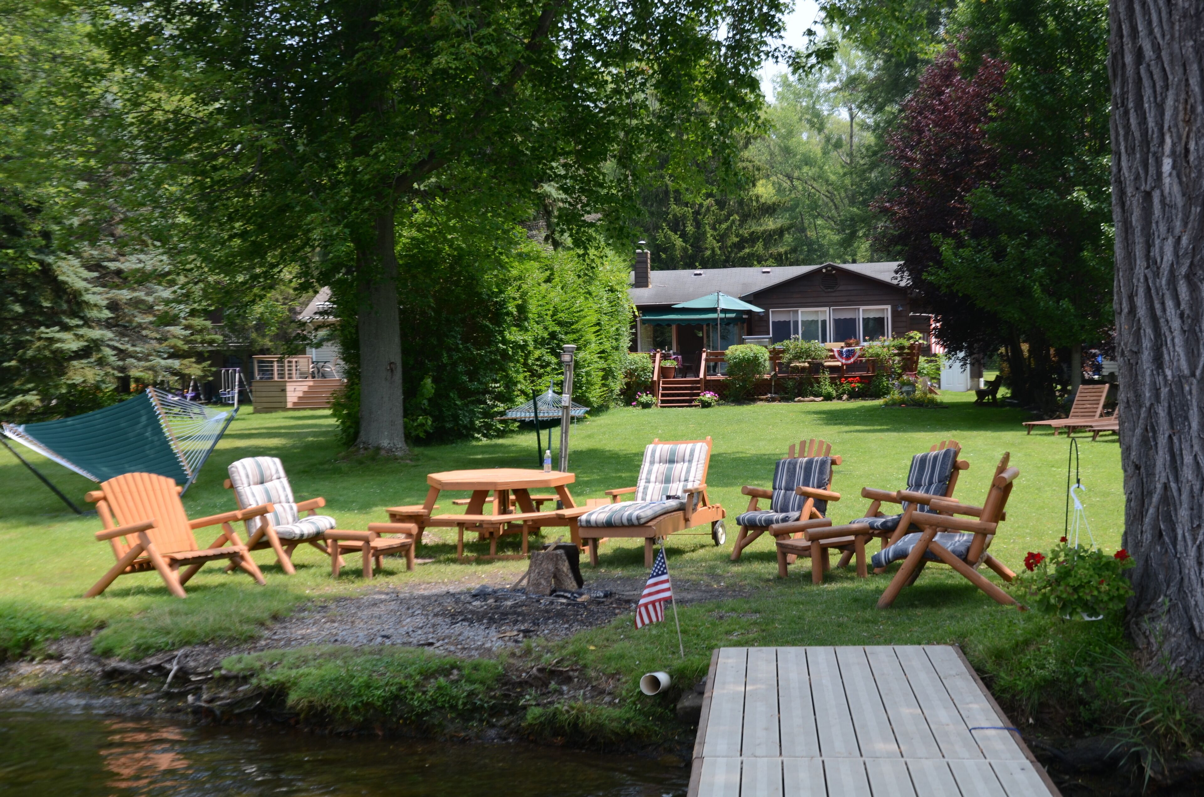Ein Garten mit einer Holzterrasse, Gartenmöbeln und einem kleinen Teich.