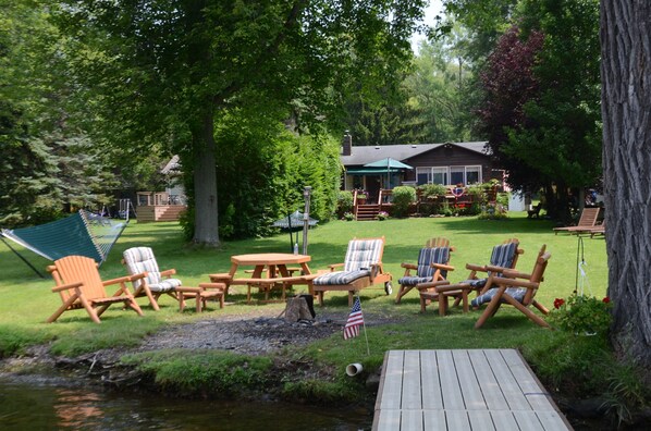 A backyard with a wooden deck, outdoor furniture, and a small pond.