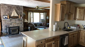 A spacious kitchen with wooden cabinets, a central island, and a stone fireplace. - September Dates Open! Year Round Fun For The Whole Family! Municipal Utilities (Honeoye)