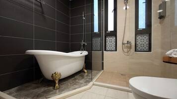 A modern bathroom with a freestanding bathtub, a glass-enclosed shower, and a separate toilet area.