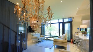 Un salon spacieux agrémenté d’un grand lustre, d’un ensemble de canapés et d’un coin repas avec une table et des chaises.