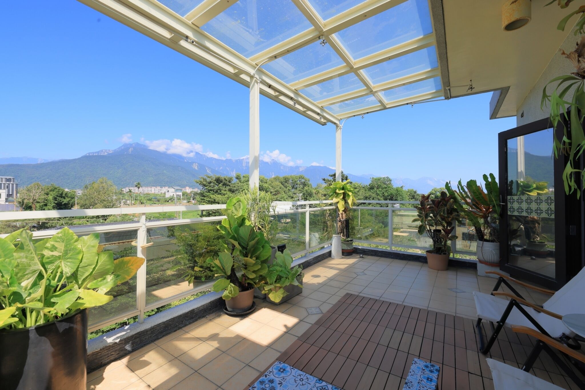 A balcony with potted plants, a view of mountains, and a clear sky.