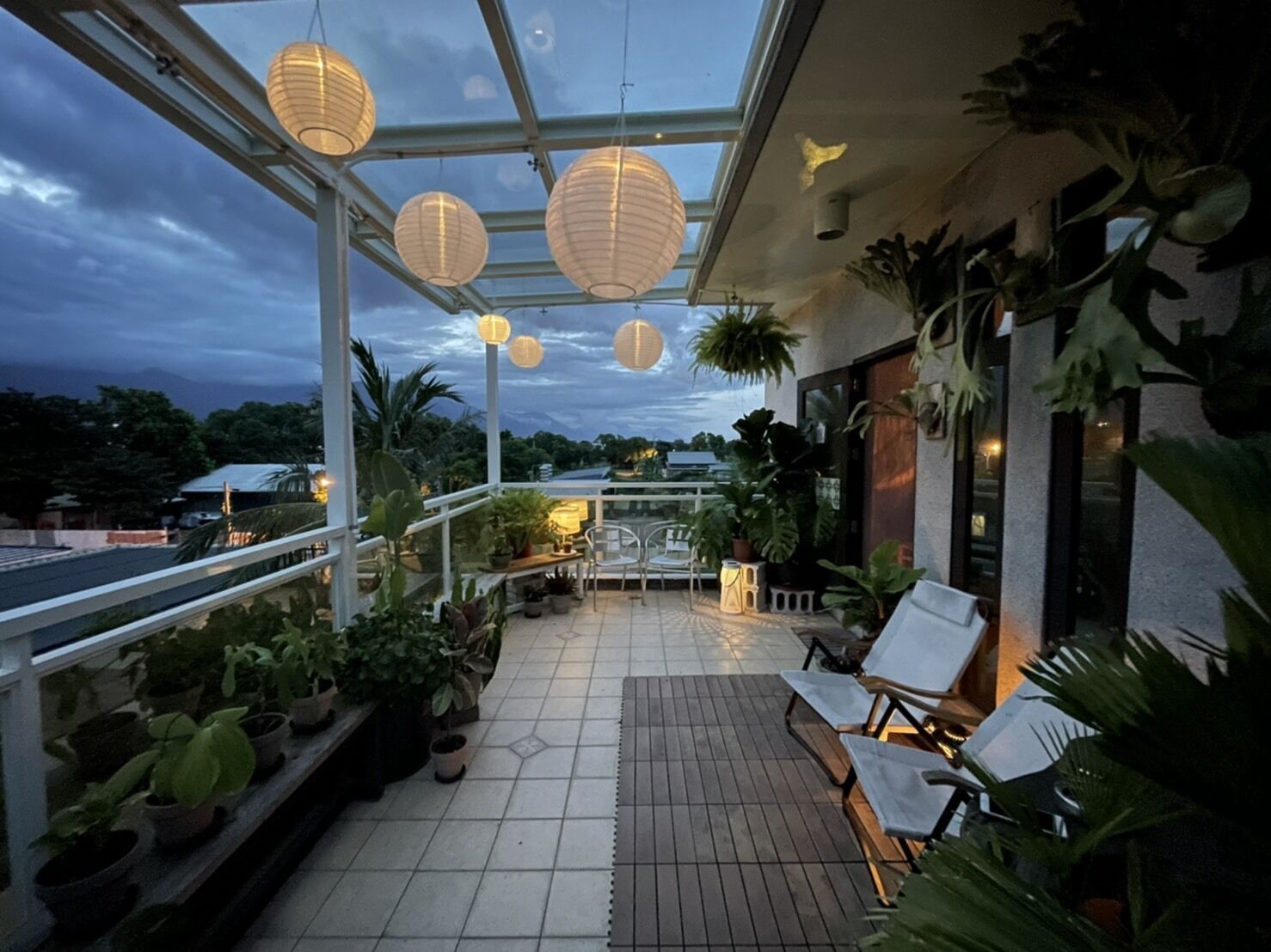 An outdoor terrace with potted plants, a seating area, and hanging paper lanterns.