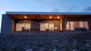 Une maison moderne dotée d’un porche abrité, de grandes fenêtres et d’un espace salon extérieur.