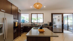 Una cocina moderna con una isla central, electrodomésticos de acero inoxidable y amplias ventanas que ofrecen luz natural.