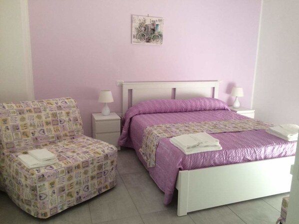 Une chambre à coucher comprenant un lit, une chaise, deux tables de chevet et un élément décoratif mural.