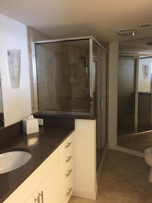 A modern bathroom with a glass-enclosed shower, a white sink, and a dark countertop.