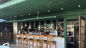 An outdoor bar area with wooden chairs, a bar counter, hanging lights, and a water feature. - Fla Keys Luxury Houseboat, Prime Location-Steps to Fun, Food & Water Adventures (Tavernier)