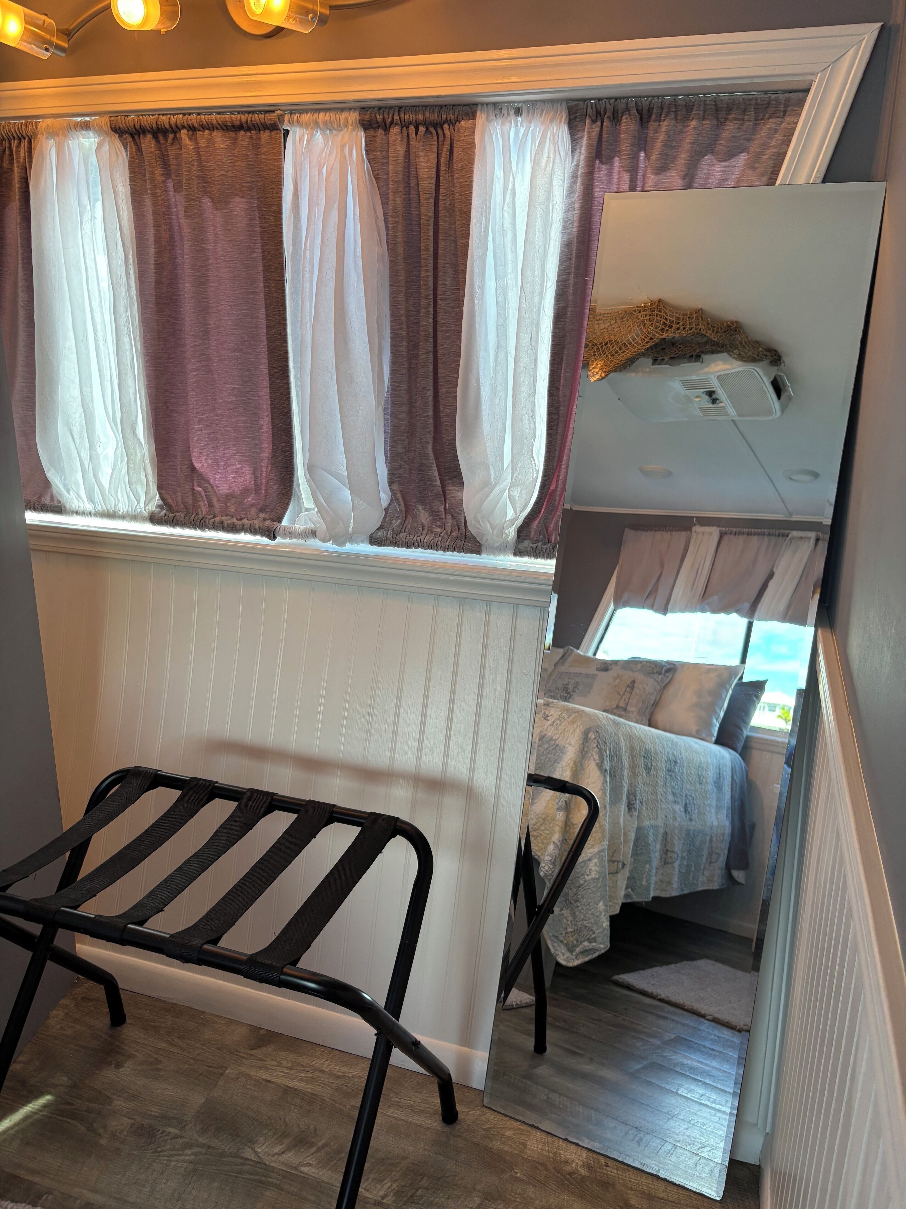 Una habitación pequeña con cama, una mesita y ventana con cortinas.