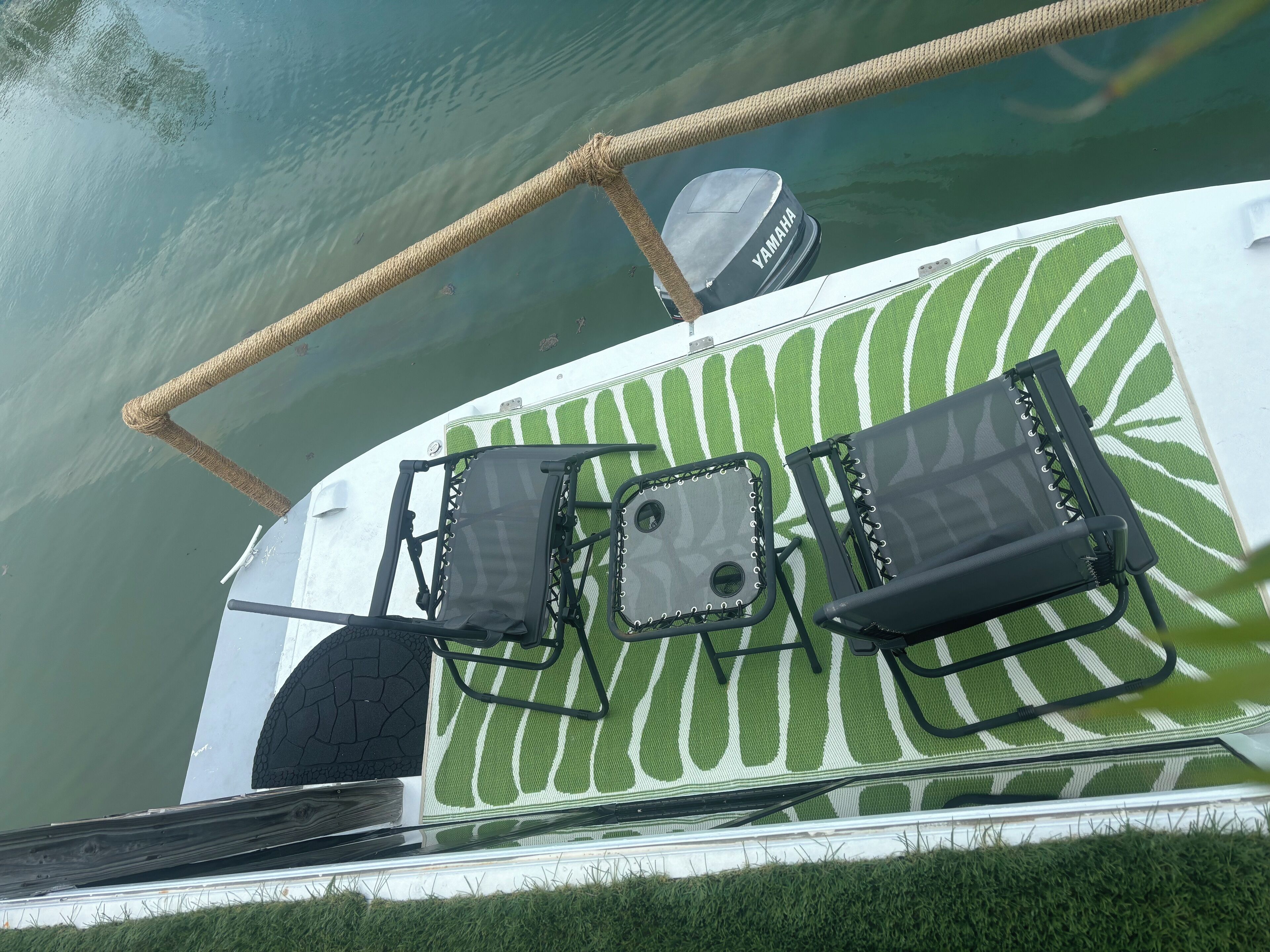 Un bateau équipé de deux fauteuils noirs rembourrés, d’un moteur hors-bord Yamaha et d’un pont orné d’un motif de feuilles vertes.