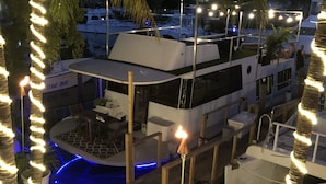 A yacht docked at a marina with a wooden deck, a pool, and string lights. - Fla Keys Luxury Houseboat, Prime Location-Steps to Fun, Food & Water Adventures (Tavernier)