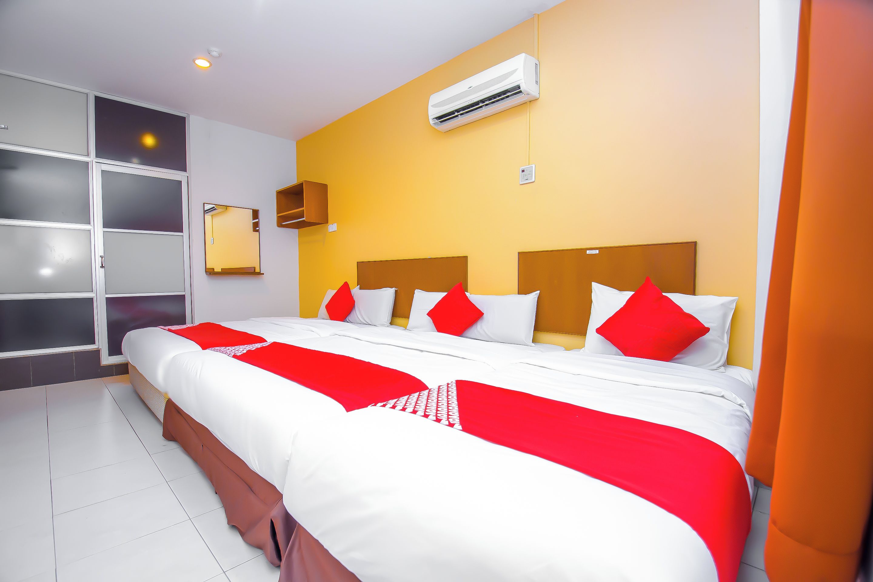 A hotel room with a large bed, a wardrobe, an air conditioning unit, and a mirror.