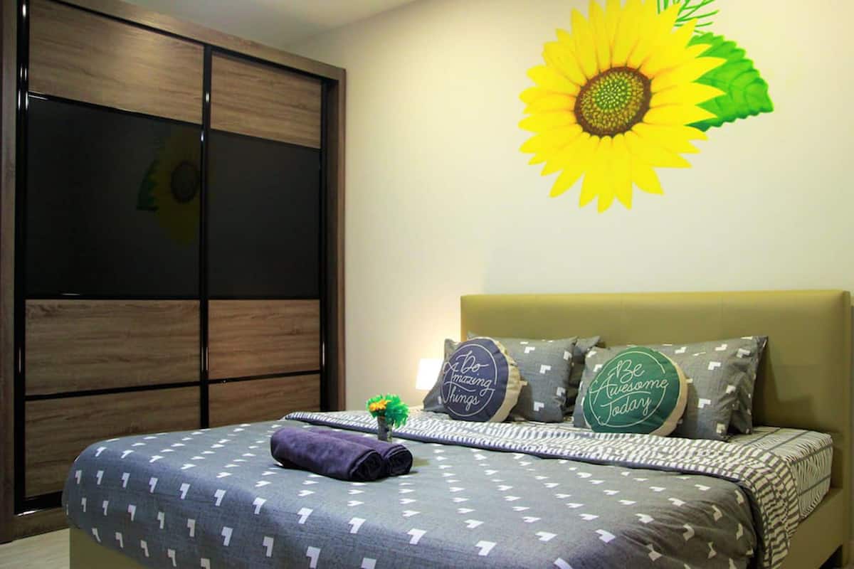 A bedroom with a bed, pillows, a wall decoration, and a wardrobe.