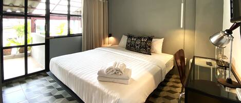Una habitación de hotel con cama, una silla, un escritorio, una lámpara y una ventana con cortinas.