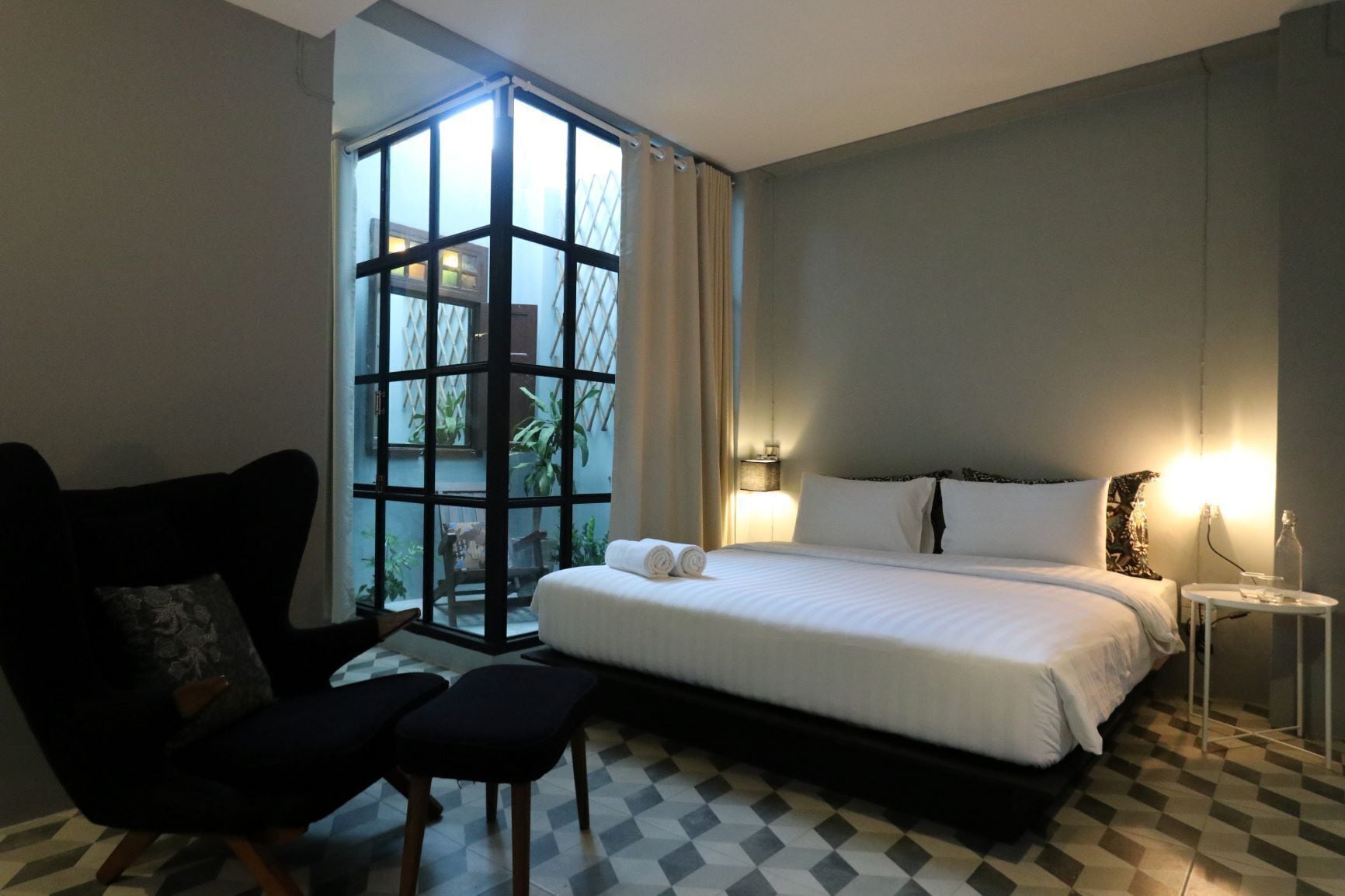 Une chambre d’hôtel avec un grand lit, une chaise, une petite table et une vue par la fenêtre.