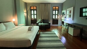 Una habitación de hotel con una cama grande, un escritorio, una silla, un televisor y una ventana con cortinas.