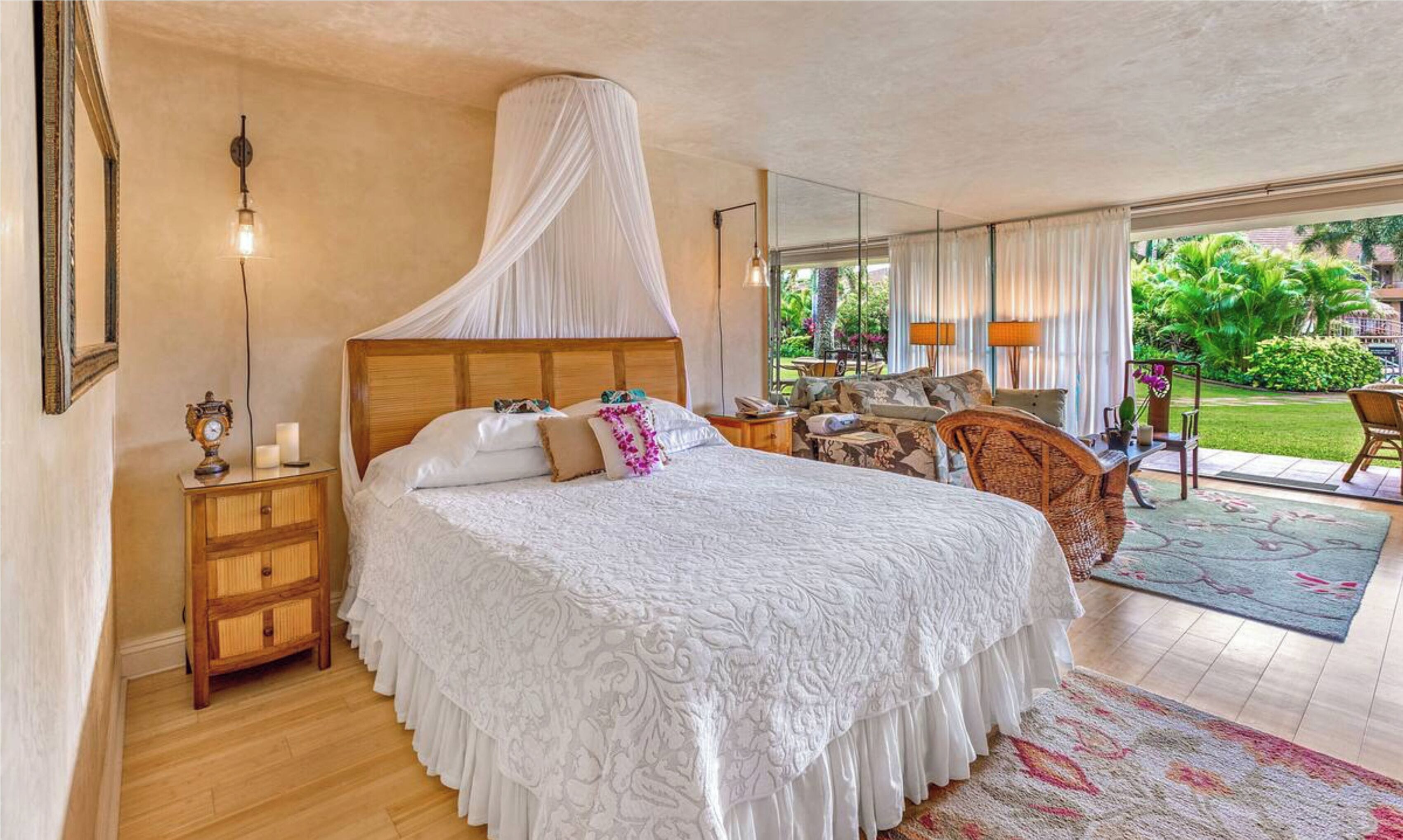 A bedroom with a canopy bed, wooden nightstands, a bedside table, a chair, and a view of the garden through large windows.