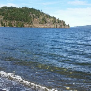 A calm lake with a forested hill in the background.