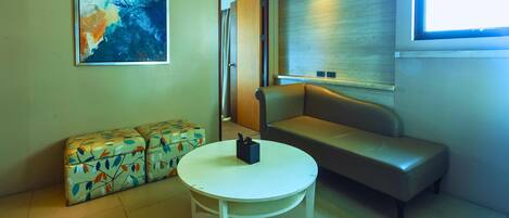 A modern room with a sofa, a round table, and a colorful patterned ottoman.