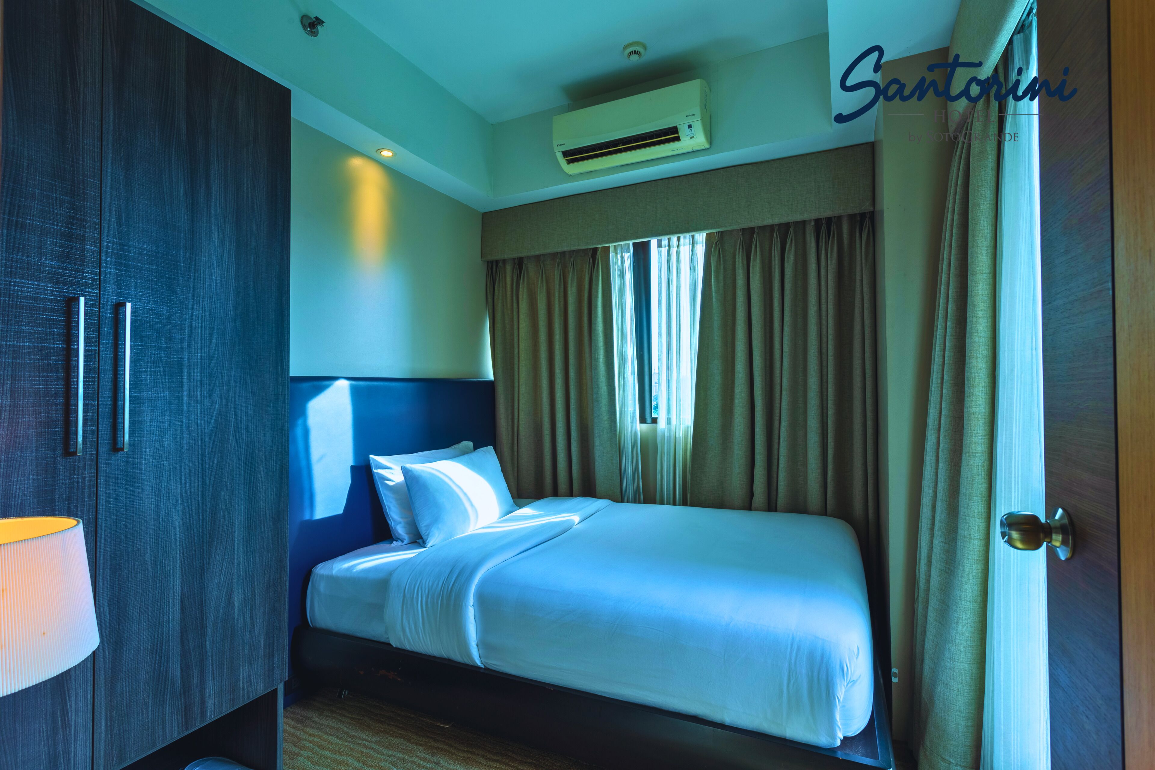 Una habitación de hotel con cama, armario y aire acondicionado.