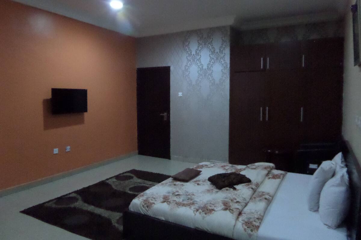 A bedroom with a bed, a TV mounted on the wall, and a wardrobe.