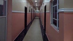 A long, narrow hallway with cream-colored walls and black-tiled floors. - Alheri Suites (Ibadan)