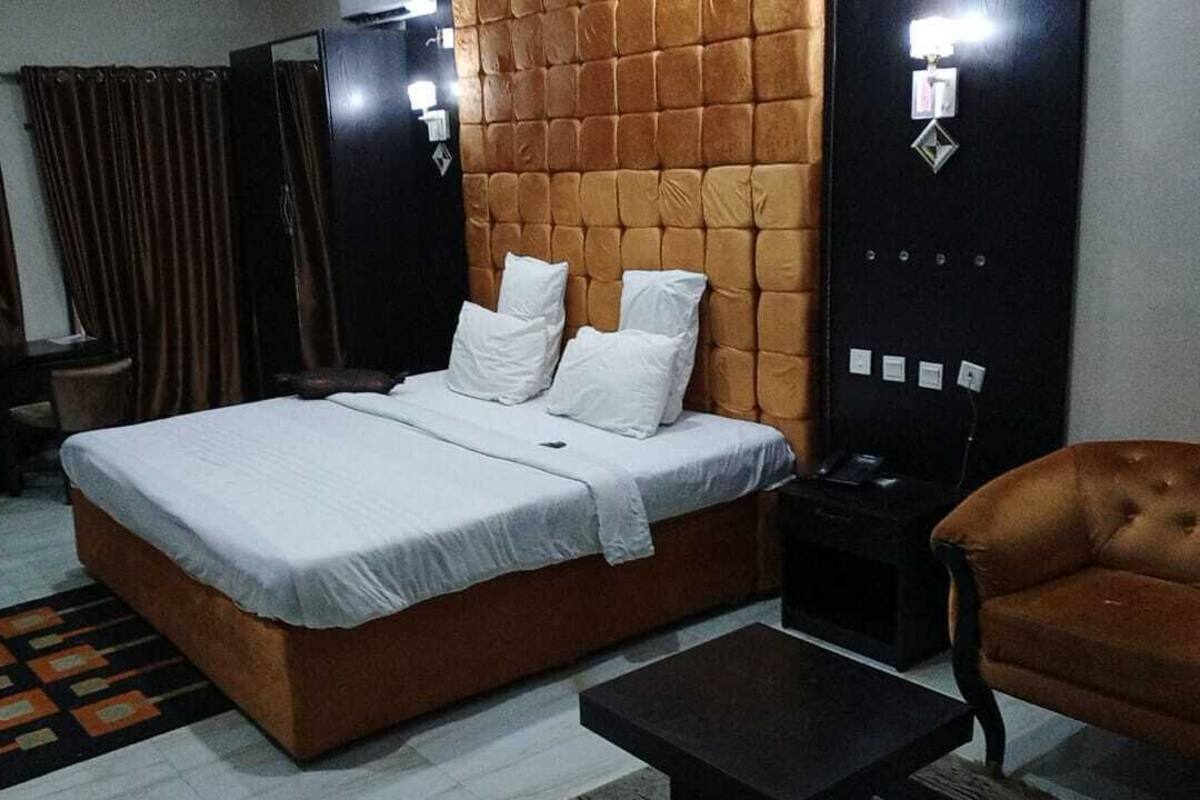 A bedroom with a bed, a nightstand, a chair, and a desk.